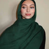 Eine Frau trägt einen dunkelgrünen Gradient-Rayon-Modalschals und blickt direkt in die Kamera.
