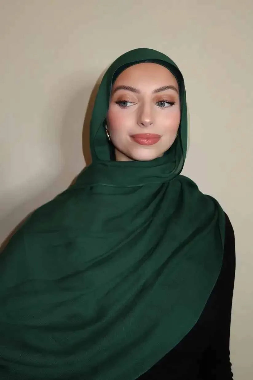 Eine Frau trägt einen dunkelgrünen Gradient-Rayon-Modalschals und blickt direkt in die Kamera.