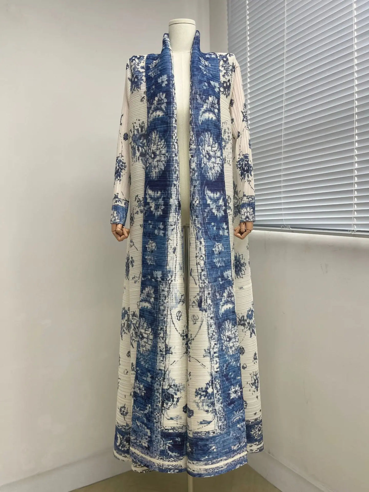Langes, fließendes, plissiertes Abaya-Cardigan mit blau-weißem Blumenmuster auf einem Mannequin.