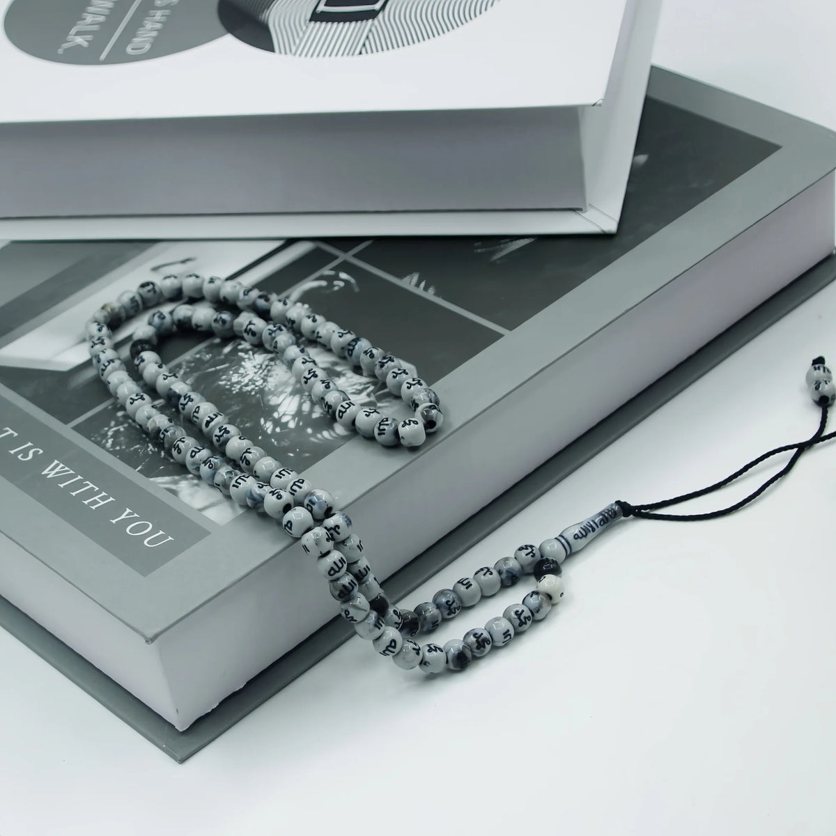 A string of dark gray beads used as an Islamic prayer tasbih for meditation and prayer resting on a book.