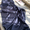 Dunkelblaue, gerüschte Satin-Chiffon-Hijab auf weißem Untergrund neben einer Box.