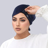 A woman wearing a navy blue adjustable elastic headband hijab cap and white top.