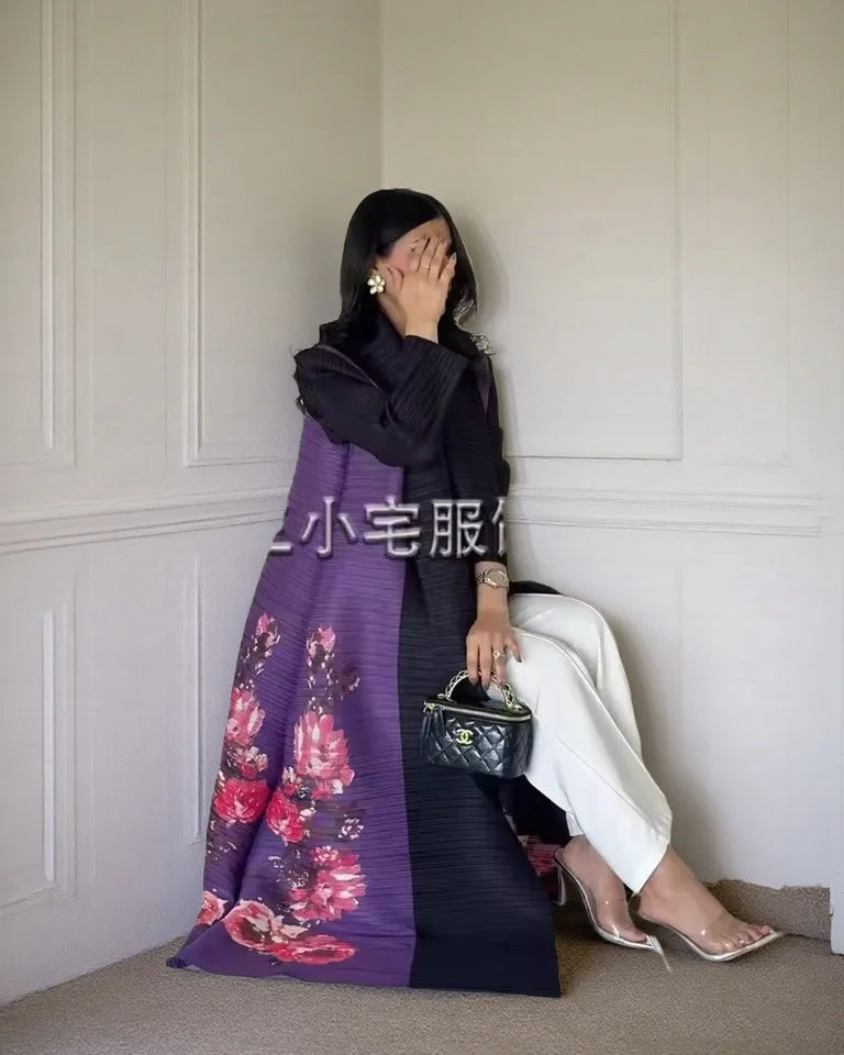 Una mujer vistiendo un cárdigan abaya plisado negro con bufanda floral morada, posando en interiores.