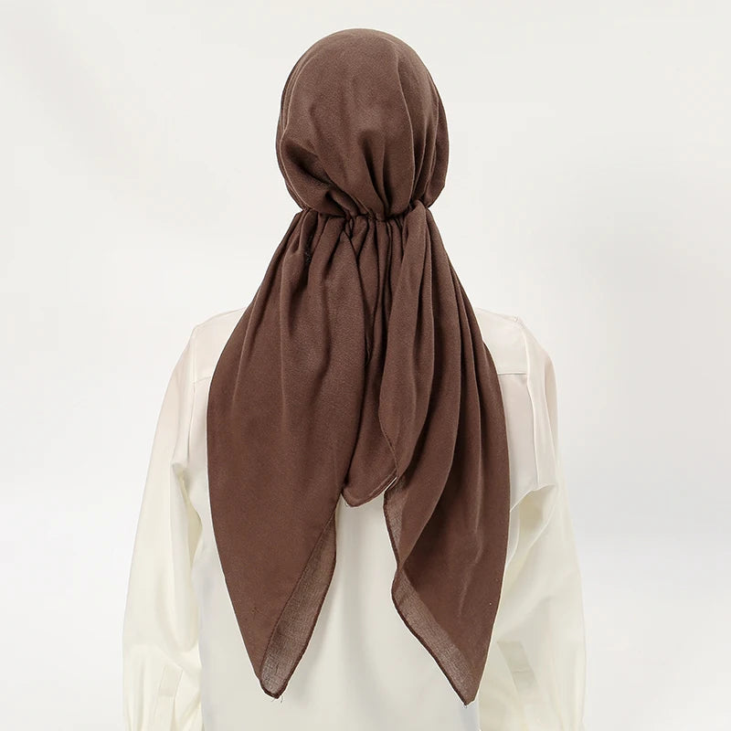 Un bonnet de hijab en lin marron drapé autour du cou d'une personne, vu de dos.