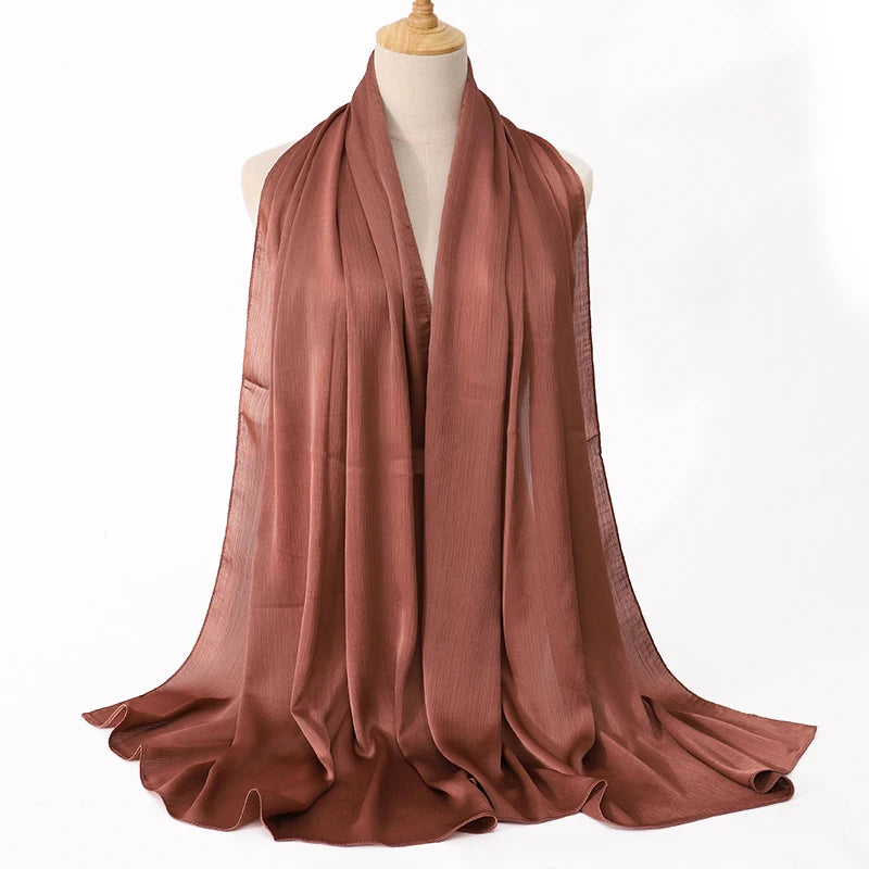 Ein drapiertes, rostfarbenes Satin-Krinkle-Hijab-Schal auf einem Mannequin.