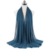 A teal chiffon hijab scarf draped around a mannequin's neck.