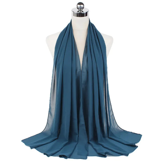 A teal chiffon hijab scarf draped around a mannequin's neck.