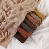 Pile de foulards ou châles en crêpe de rayon aux tons terreux : beige, olive et rouille.