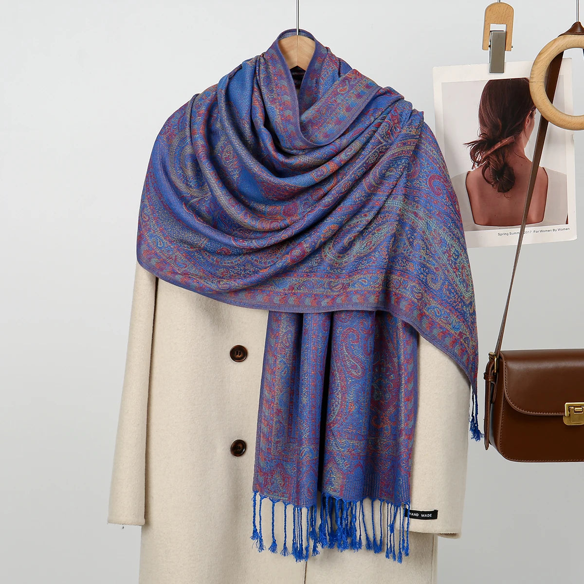 Chal de bordado paisley azul y morado sobre un blazer beige.