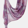 A flowing, sheer lilac and purple printed linen hijab scarf draped elegantly.