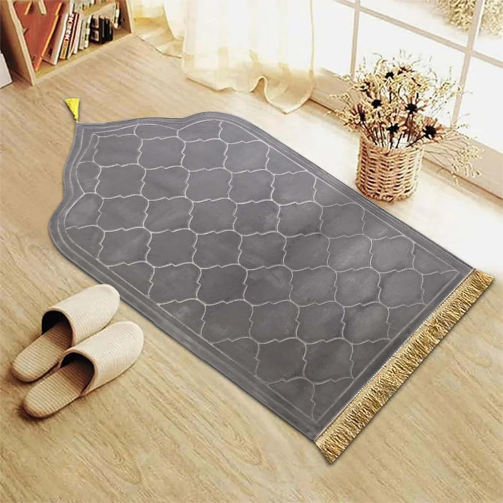 Grauer Gebets-Teppich mit geometrischem Muster und goldenen Fransen auf hellem Holzfußboden.