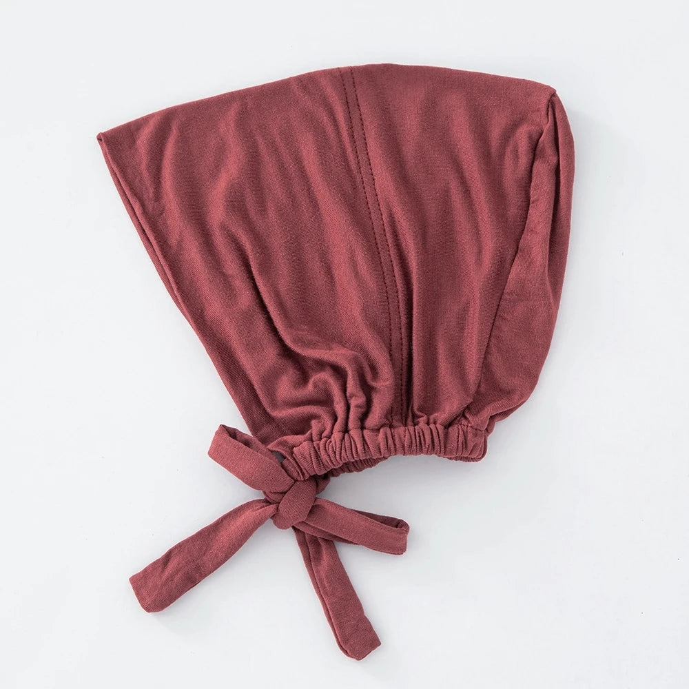 Ein passendes inneres Hijab-Bonnet mit gebundener Stoff in terracotta-roter Farbe.