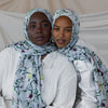 A woman wearing a watercolor printed scarf hijab and white clothing.