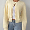 Une femme portant un pull en tricot jaune pâle sur un haut blanc et un jean.