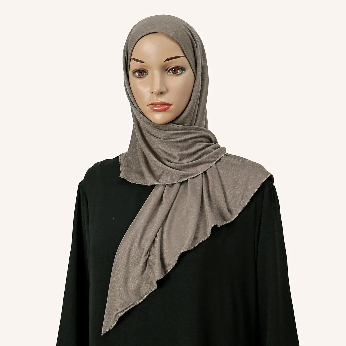 Eine Frau modelliert einen weichen grauen Modal-Jersey-Instant-Hijab-Schal um ihren Hals vor schwarzem Hintergrund.