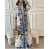 Une femme modélise une veste coupe-vent plissée à motif floral crème et bleu avec des accessoires dorés.