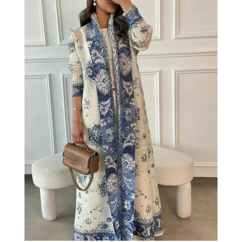 Une femme modélise une veste coupe-vent plissée à motif floral crème et bleu avec des accessoires dorés.