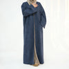 A woman wearing an elegant navy blue abaya trench coat over a beige garment.