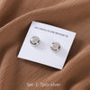 A set of two silver no-snag hijab magnets is displayed on a white card against a brown fabric background.