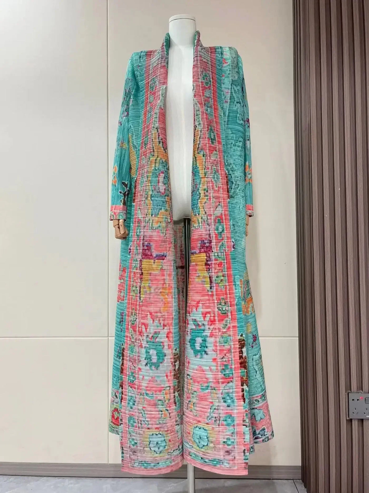 Manteau long à col de pie, à manches longues, à plis, rose et sarcelle, présenté sur un mannequin.