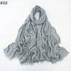 Un foulard hijab en coton viscose gris doux, drapé et plié sur fond blanc.