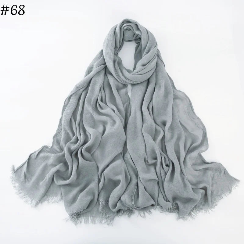 Un foulard hijab en coton viscose gris doux, drapé et plié sur fond blanc.