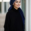 Una mujer vistiendo un hijab azul oscuro y ropa negra con una diadema de diamantes brillantes.