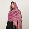 Una mujer modela un pañuelo pashmina de lujo rosa y morado drapeado sobre su cabeza y hombros.