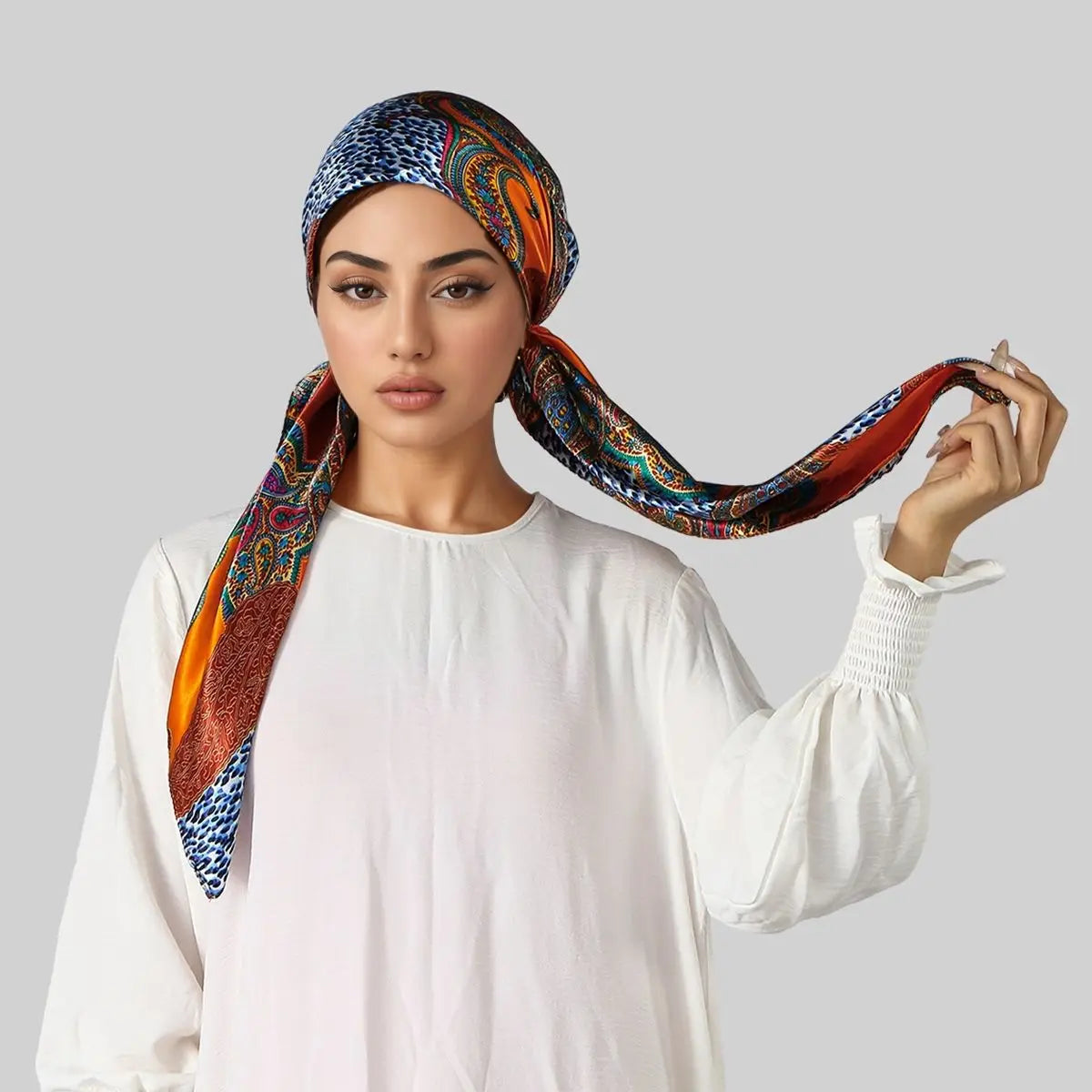 Eine Frau modelliert einen orange-blauen Seiden-Instant-Hijab-Schal, getragen auf dem Kopf und über die Schulter drapiert.