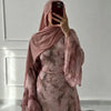 Eine Frau trägt ein fließendes, durchscheinendes Blumenmuster-Abaya und Kaftan in staubiges Rosé.