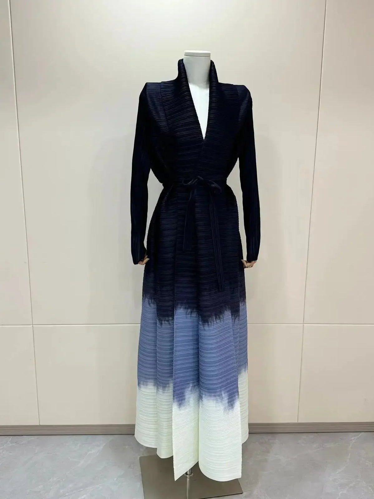 Manteau trench à manches longues à plis imprimé bleu foncé exposé sur un mannequin.