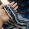 Una mano sostiene un rosario de 99 cuentas musulmanas con borlas de luna y estrella.