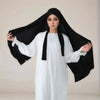 Eine Frau in einem weißen langen Kleid und einem schwarzen Instant-Hijab mit Riemchen.