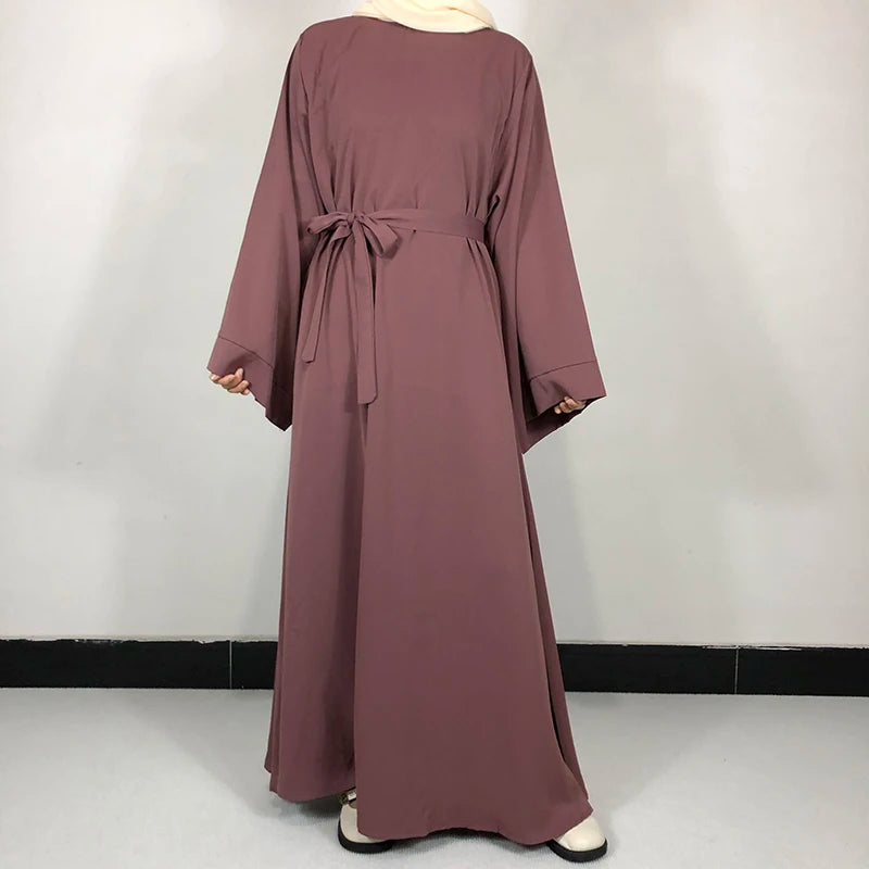 Une robe abaya mauve uni portée par un mannequin, avec un détail de ceinture nouée.