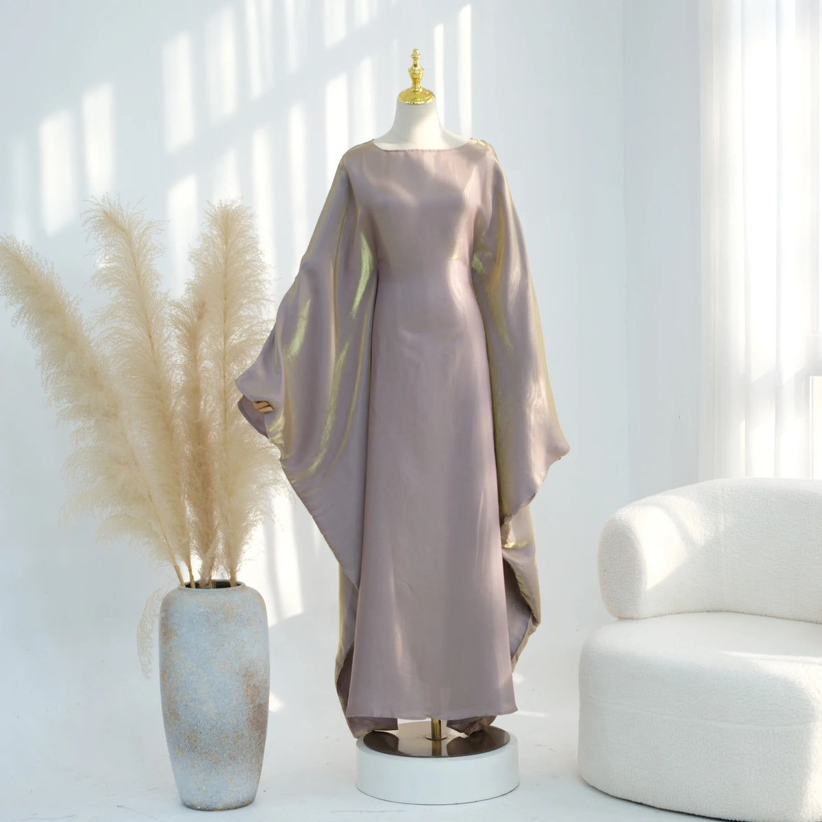 Mauve Kaftan-Kleid mit Schmetterlingsärmeln auf einem Mannequin neben getrocknetem Pampasgras.
