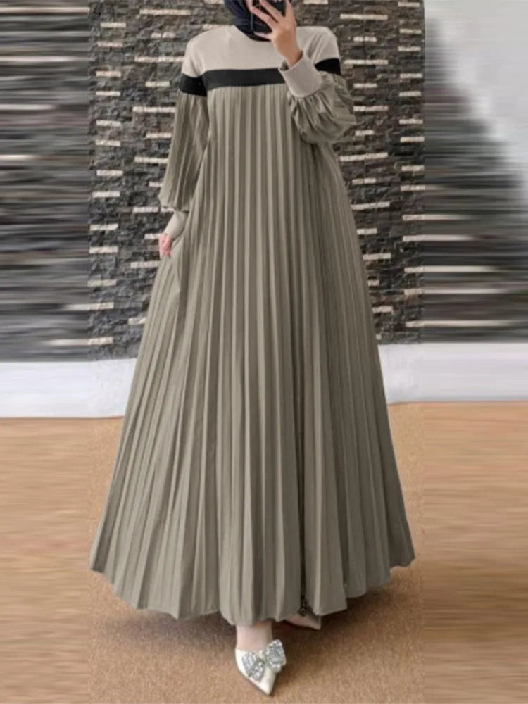 Femme portant une caftan longue, fluide, patchwork vert olive avec plis verticaux et un col beige.