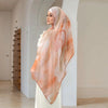A woman wearing an elegant printed linen hijab scarf in soft peach and cream tones.