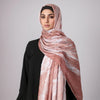 Eine Frau trägt einen rosa-weißen Aquarell-Schal mit Hijab und ein schwarzes Oberteil.