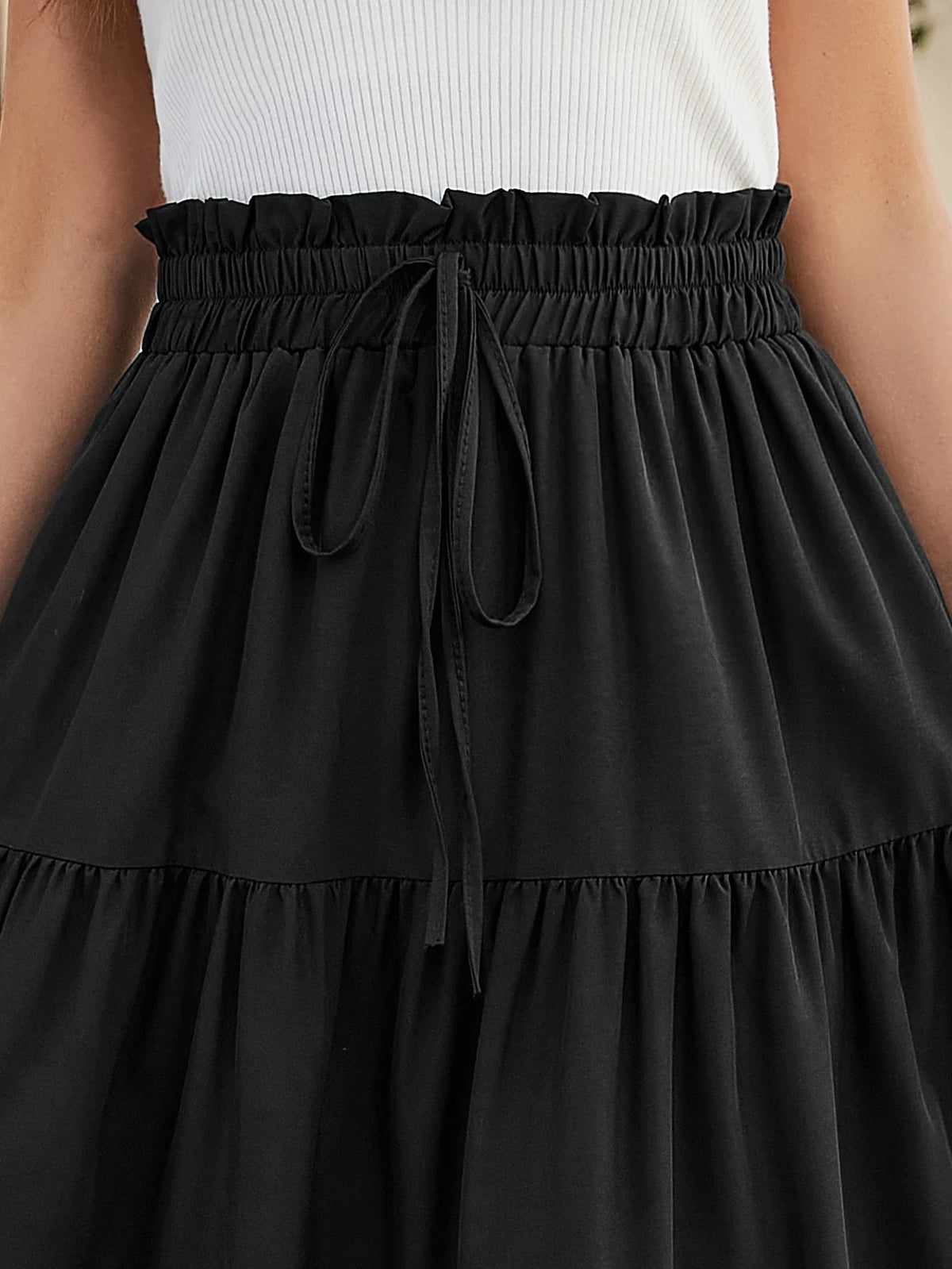 Una falda midi A-line bohemia negra atada a la cintura, usada por una persona.
