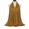 A woman wearing a flowing, olive gold soft modal jersey hijab scarf draped in a V-neck style.