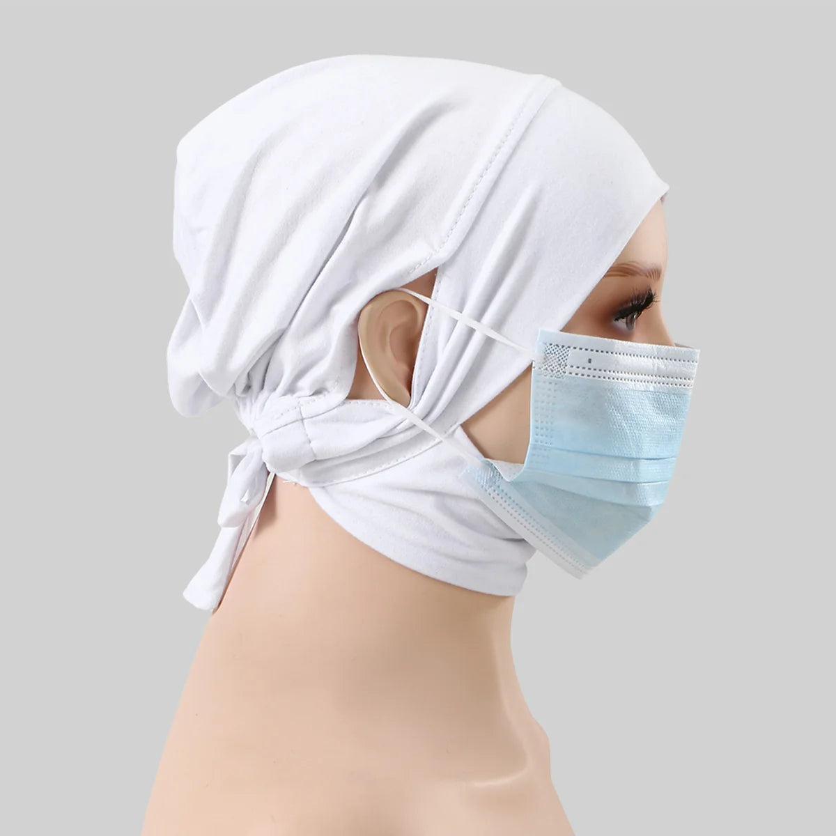 Ein weißes Baumwoll-Hijab-Cap in Jersey wird auf einem Mannequin getragen, mit einer hellblauen chirurgischen Maske sichtbar.