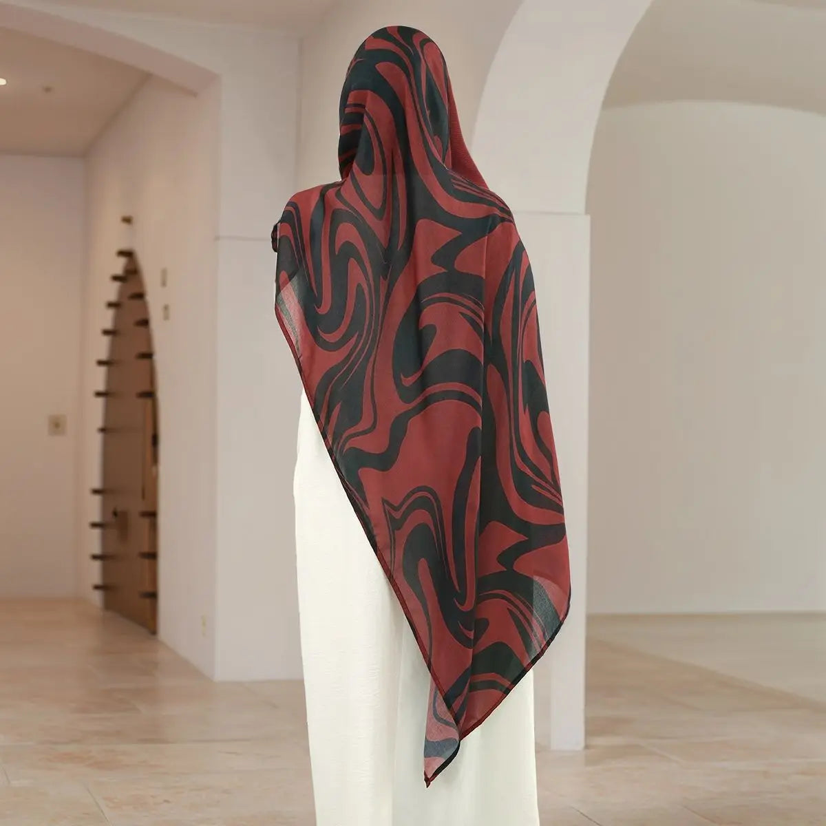 Tiefrote und schwarze abstrakte Hijab-Schal, drapiert auf einem weißen Ständer.