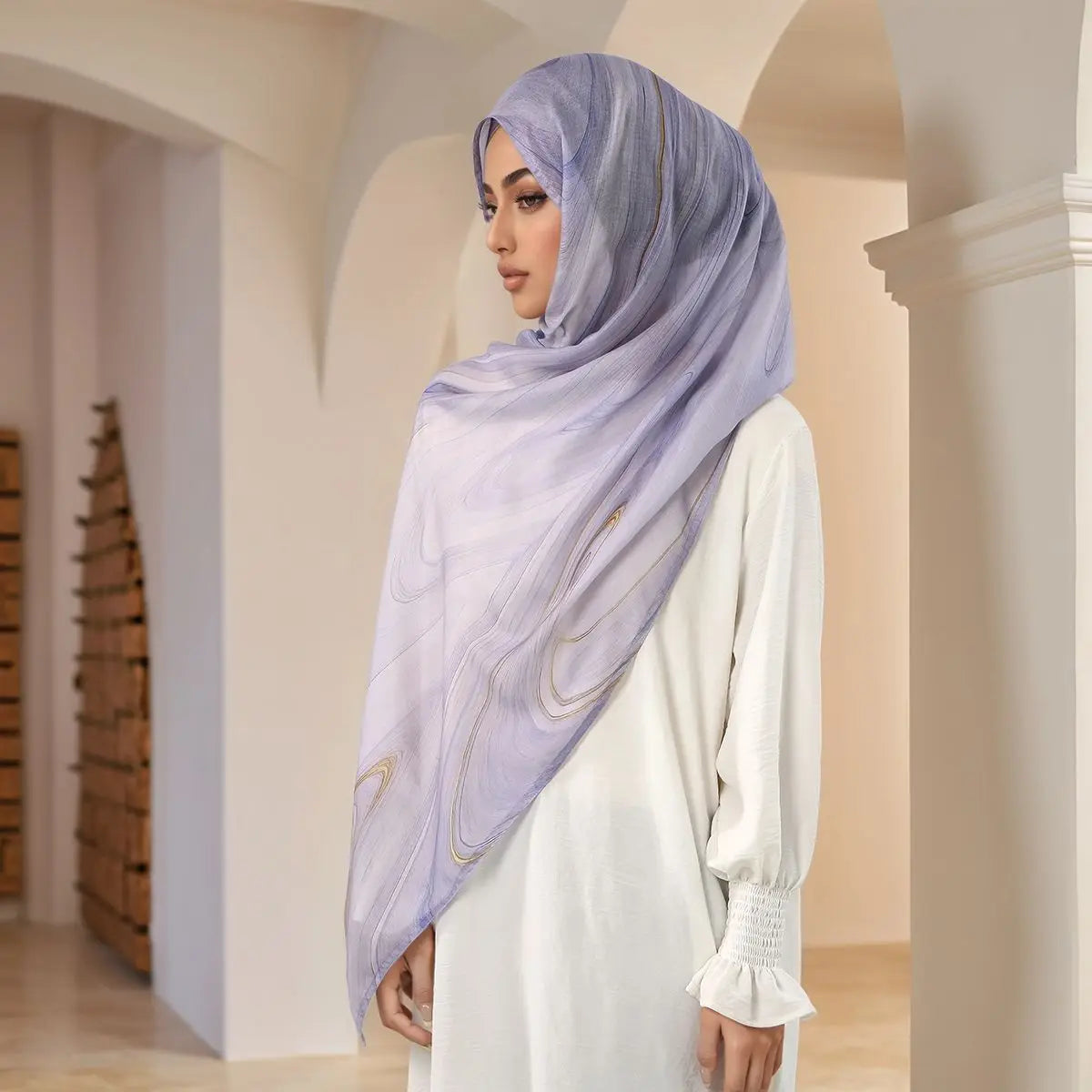 Eine Frau trägt einen helllila bedruckten Baumwoll-Rayon-Hijabschal in einem gewölbten Flur.