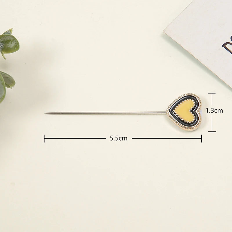 Un set de alfileres para hijab de seda con estampado de mariposa y un corazón dorado en un alfiler plateado.