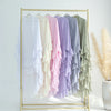 A display of ruffled two-layer chiffon hijabs in pastel shades hanging on a gold hanger rack.