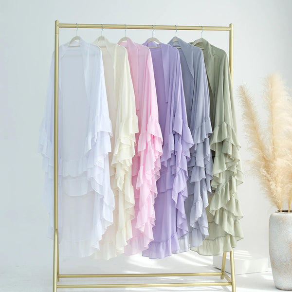 A display of ruffled two-layer chiffon hijabs in pastel shades hanging on a gold hanger rack.