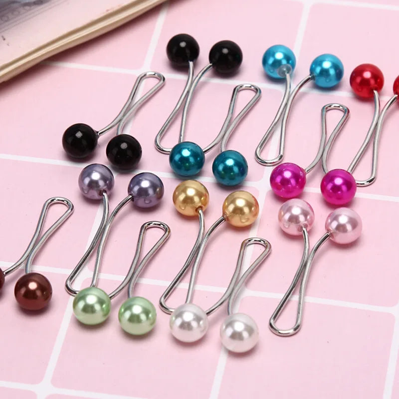 Eine Sammlung von silbernen Drop-Pins mit verschiedenen farbigen Kunstperlen, darunter schwarz, blau, pink und weiß.