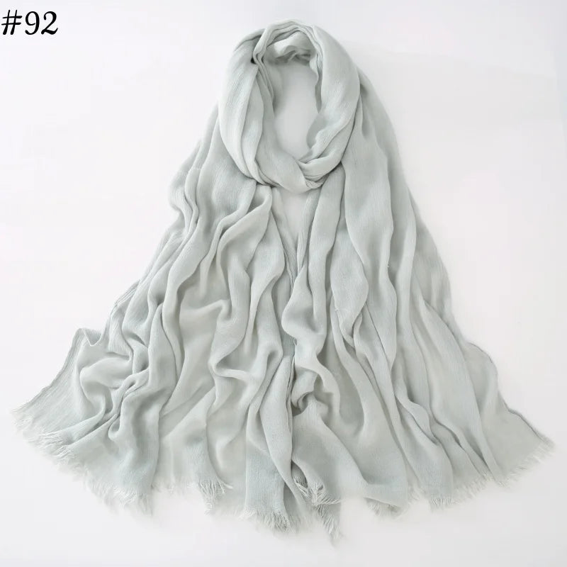 Un foulard hijab en coton viscose gris clair, drapé élégamment sur fond blanc.