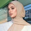 Una mujer vistiendo un hiyab beige instantáneo, mirando a un lado.