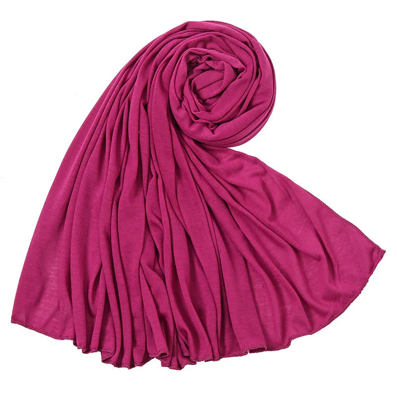 Un foulard hijab en jersey de coton magenta profond roulé en spirale décorative.
